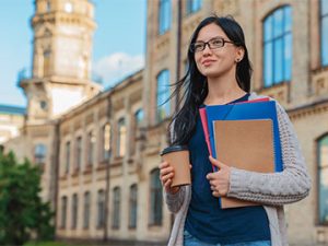 女学生持有文件夹和咖啡并步行医院